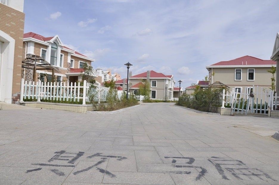 一座海景别墅的入口处,地上用黑色油漆写着"欺骗"二字,该别墅群建成