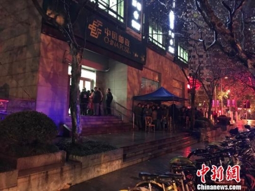 　　1月5日清晨5点半，在上海静安邮政支局，市民冒着寒风与冷雨，撑伞排队，抢购首发的戊戌狗年生肖邮票。　郭容 摄