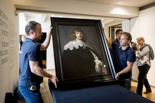 阿姆斯特丹隐士庐博物馆工作人员正在展示《年轻绅士的肖像》