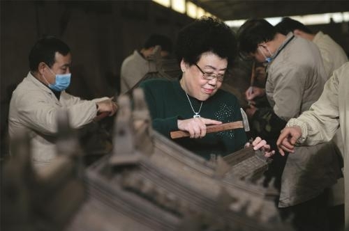 陈丽华女士示范安装影壁上的吞脊兽。中国紫檀博物馆供图